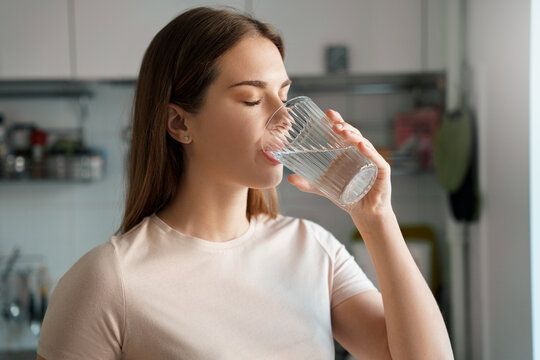 En kvinne drikker et glass vann for å lindre munntørrhet.